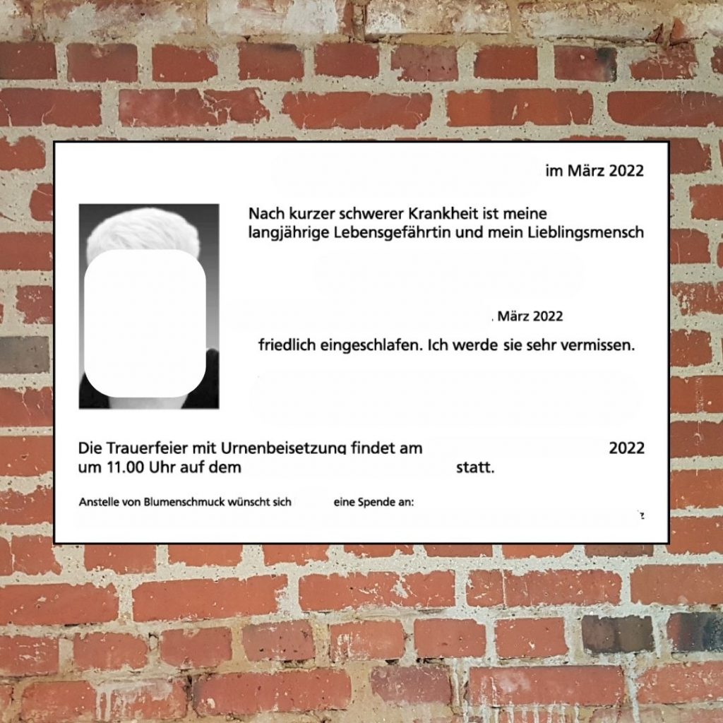 Todesanzeige mit ausgeweißten personenbezogenen Daten auf einem Steinwand-Hintergrund